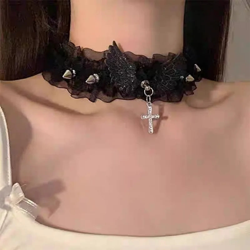 Black velvet choker necklace with lace, wing detail, silver studs, and dangling cross pendant